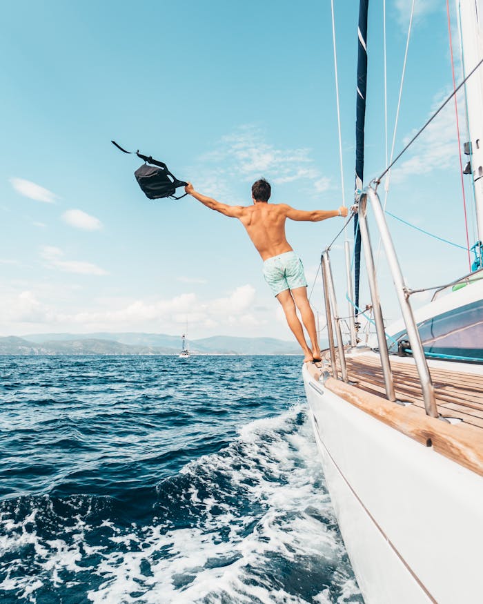 Home Man enjoying freedom by jumping into the ocean from a sailboat in Greece.